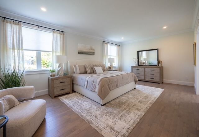First-floor primary suite bedroom with king bed and tray ceiling in a 55+ active adult condominium at Trailside Estates