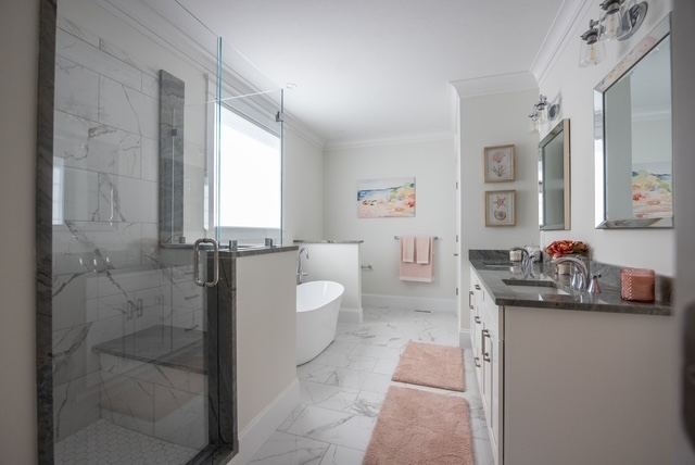 Spa-style first-floor primary bath with marble walk-in shower and soaking tub at Trailside Estates 55+ community